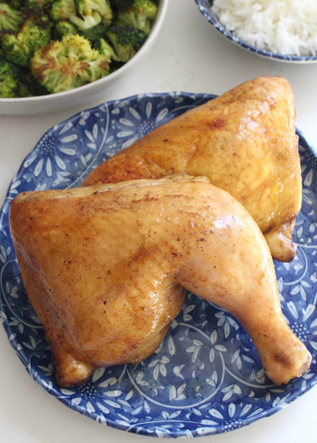 Two chicken legs are sitting on a blue and white plate.