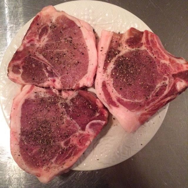 Three chops of meat on a white plate on a table
