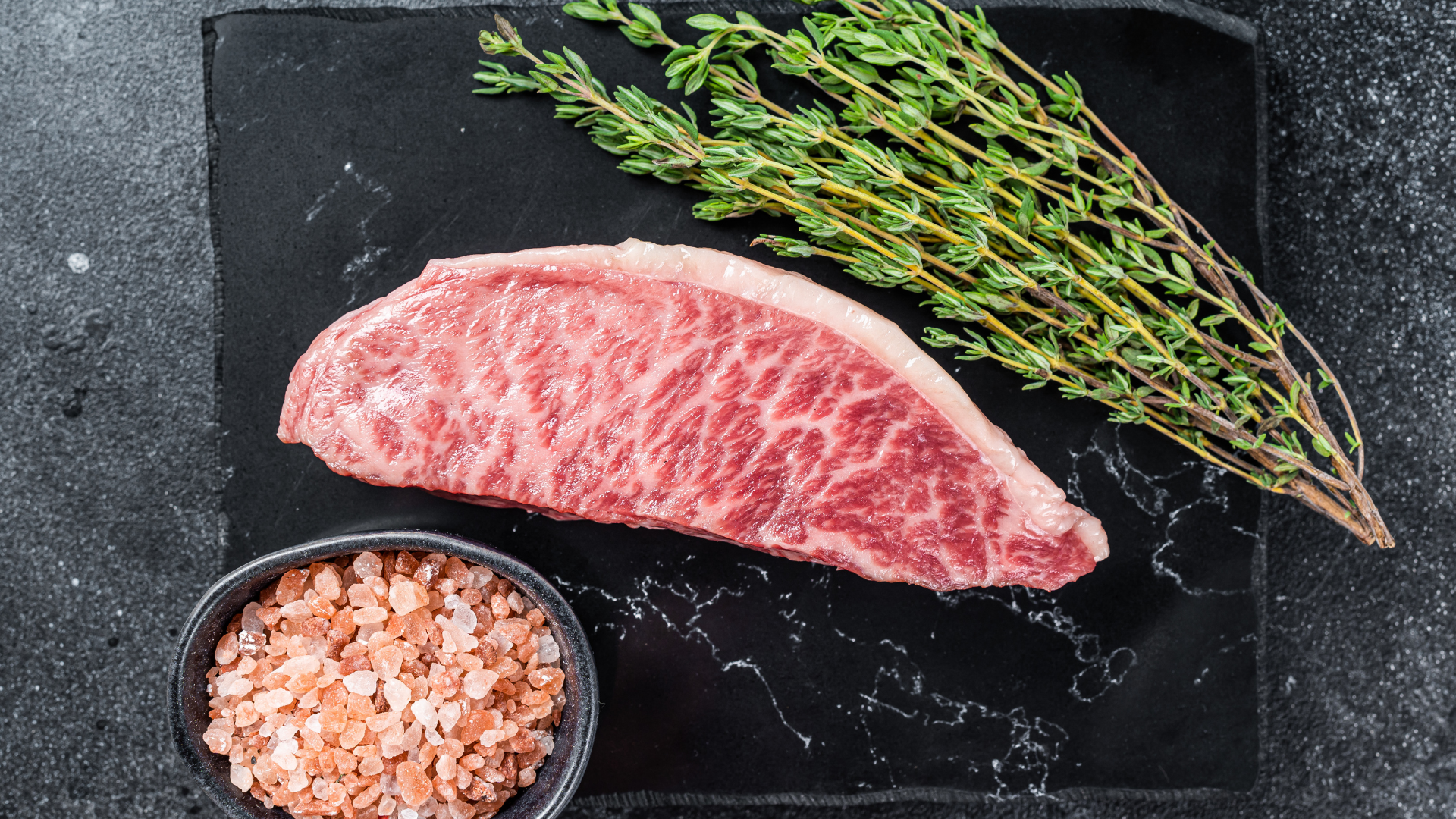 A steak is in a plastic bag on a wooden table.