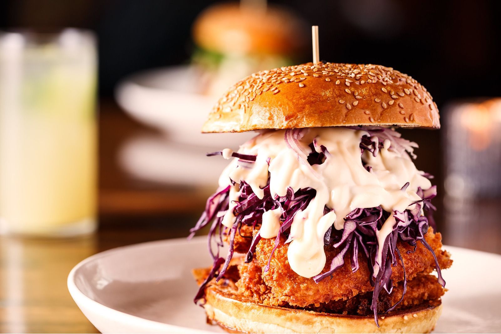 A fried chicken sandwich with coleslaw and mayonnaise on a white plate.