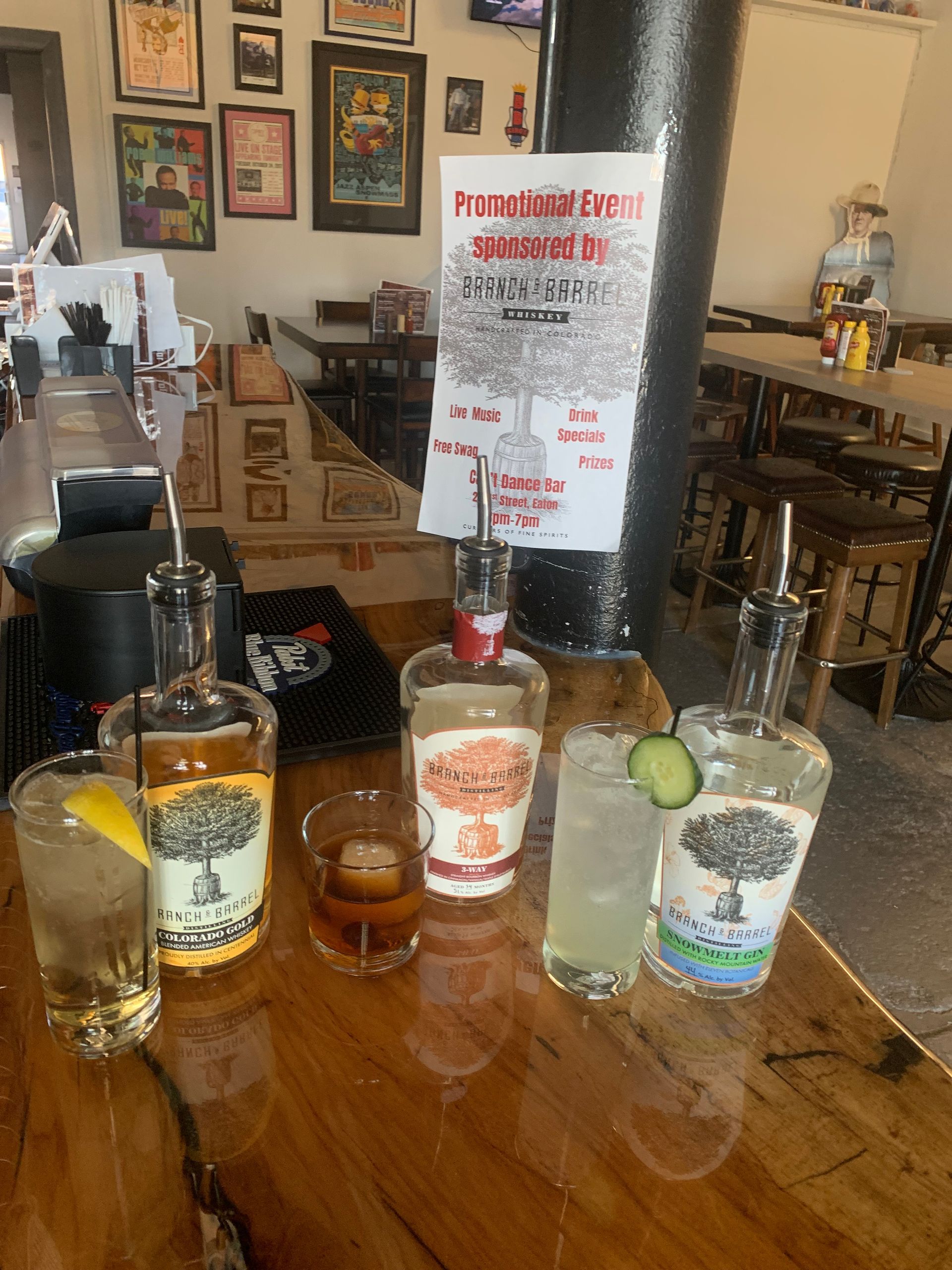 Bar with cocktails, bottles of liquor, and a promotional sign.