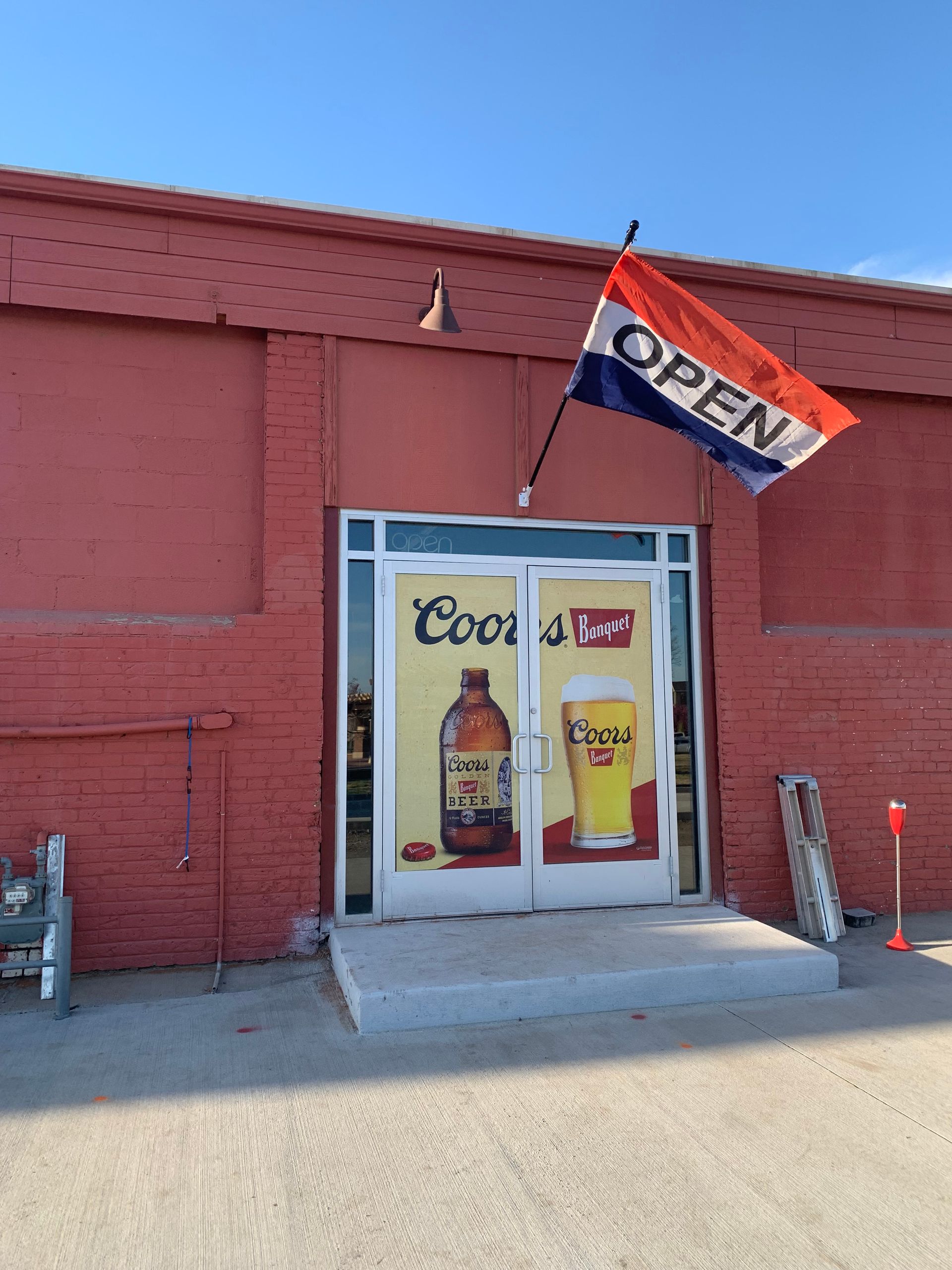 Red brick building with open sign and Coors Light advertisement on the door.