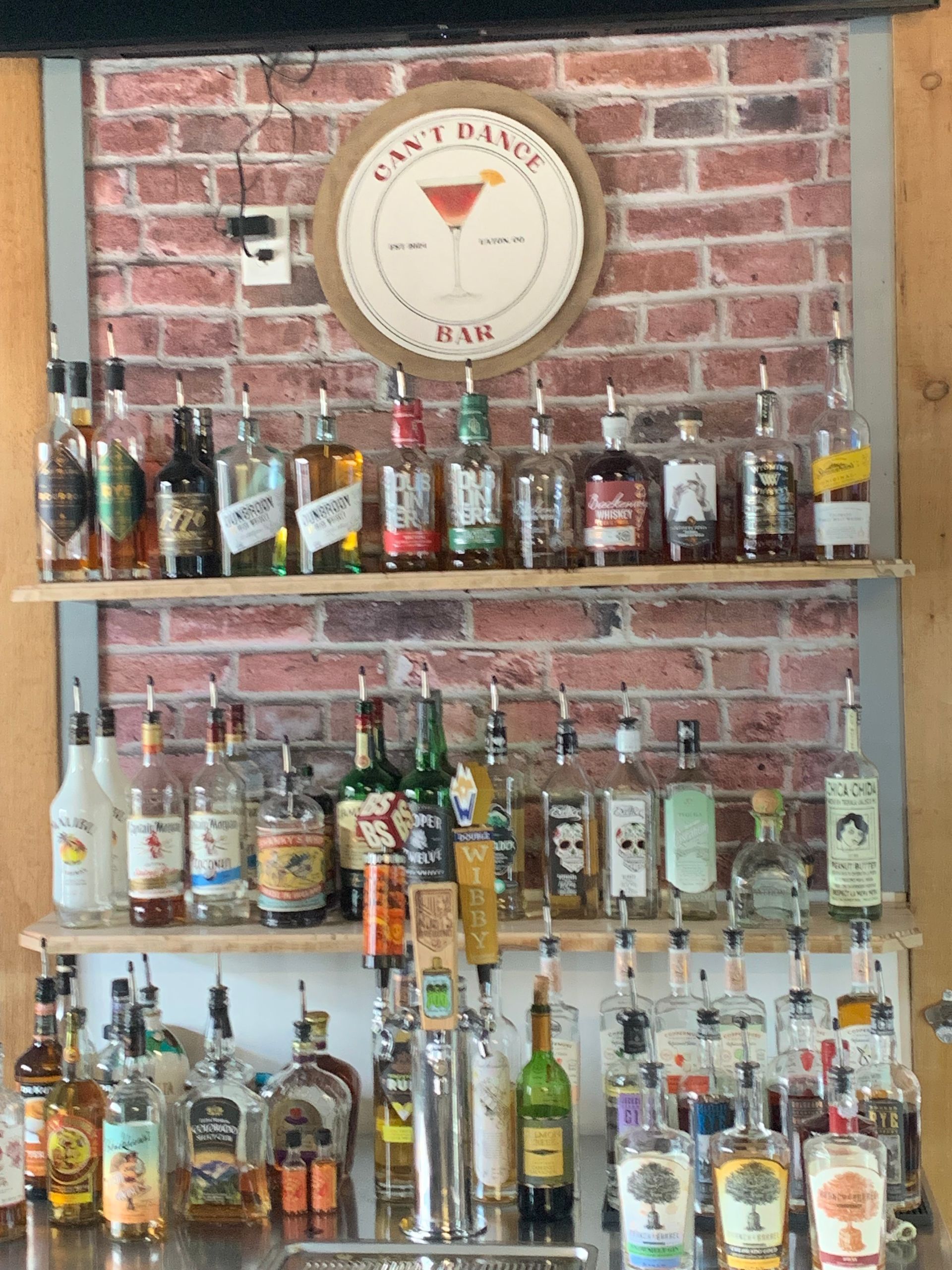 Bar with liquor bottles on shelves against a brick wall. 