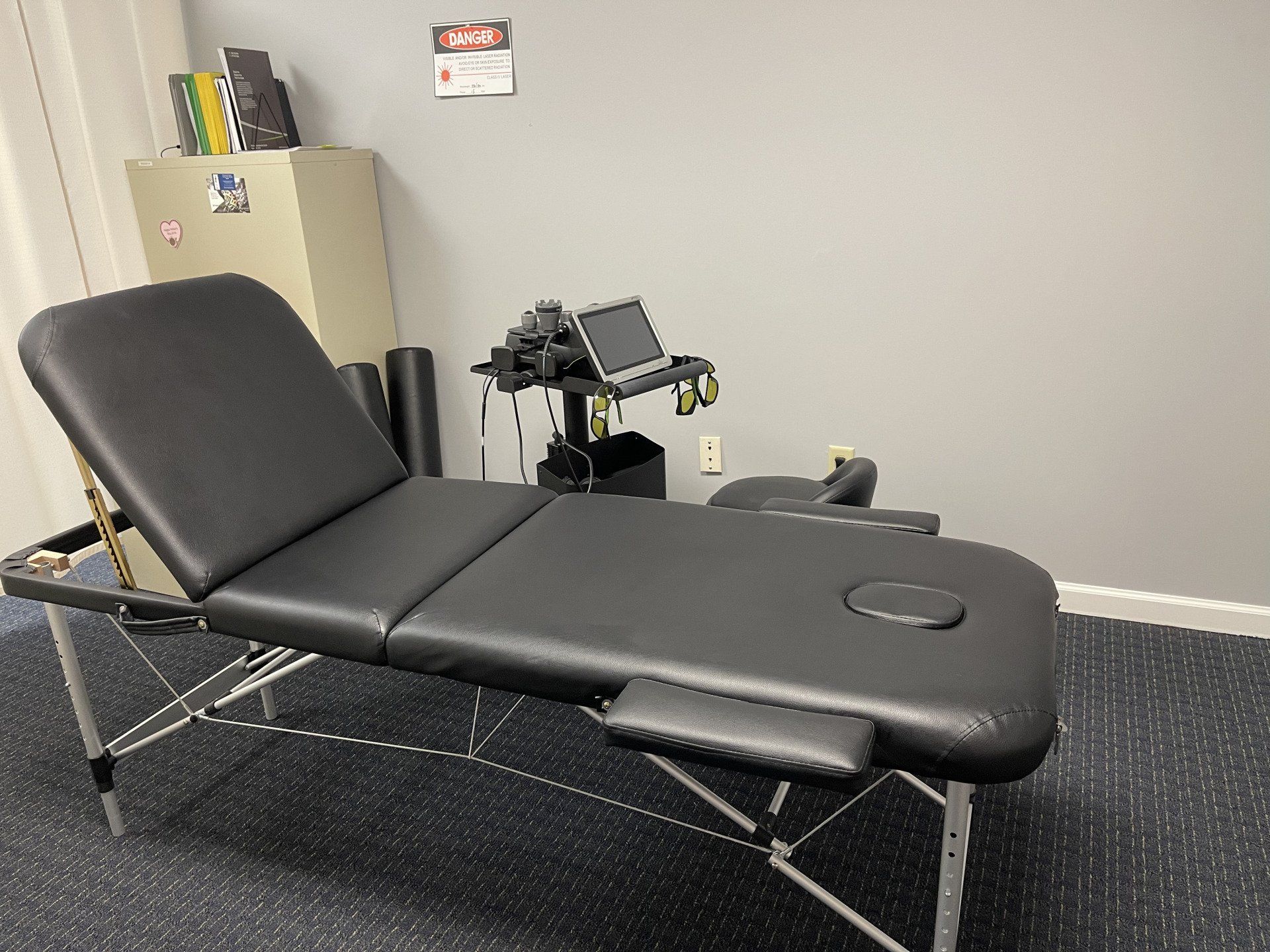 Black massage table in a therapy room with equipment.