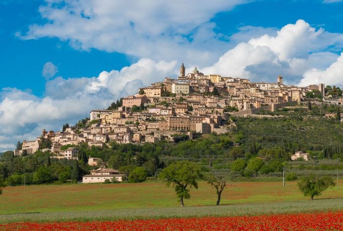 Villaggio collinare con edifici in pietra che si affacciano su campi verdi