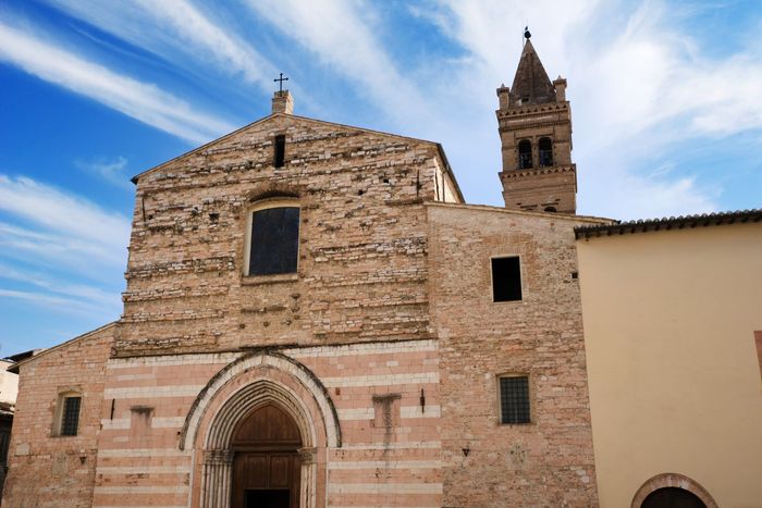 Facciata in pietra della chiesa con portale ad arco e campanile