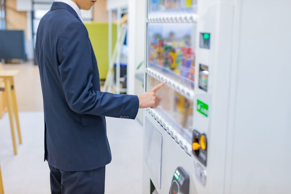 Person in a blue suit at a vending machine, selecting a product.