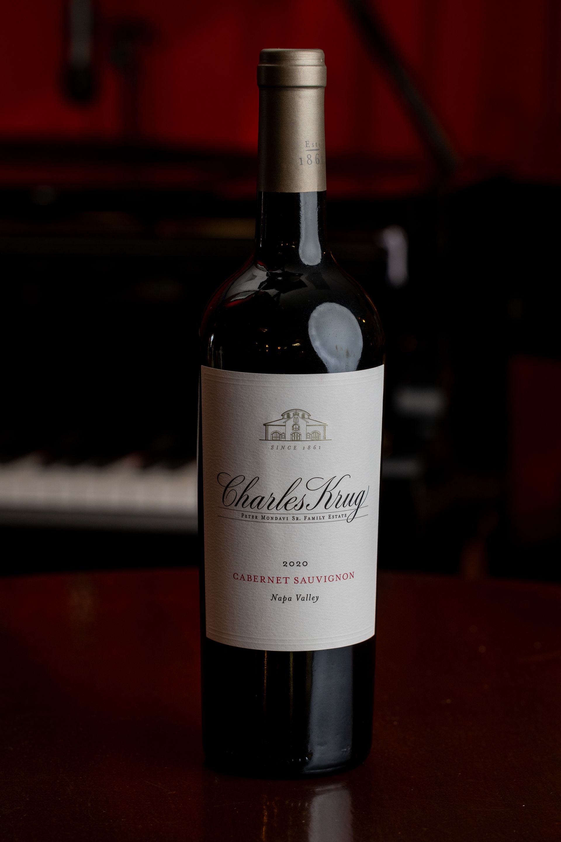 A bottle of wine on a wooden table in front of a piano at All That Jazz Dinner and Live Music