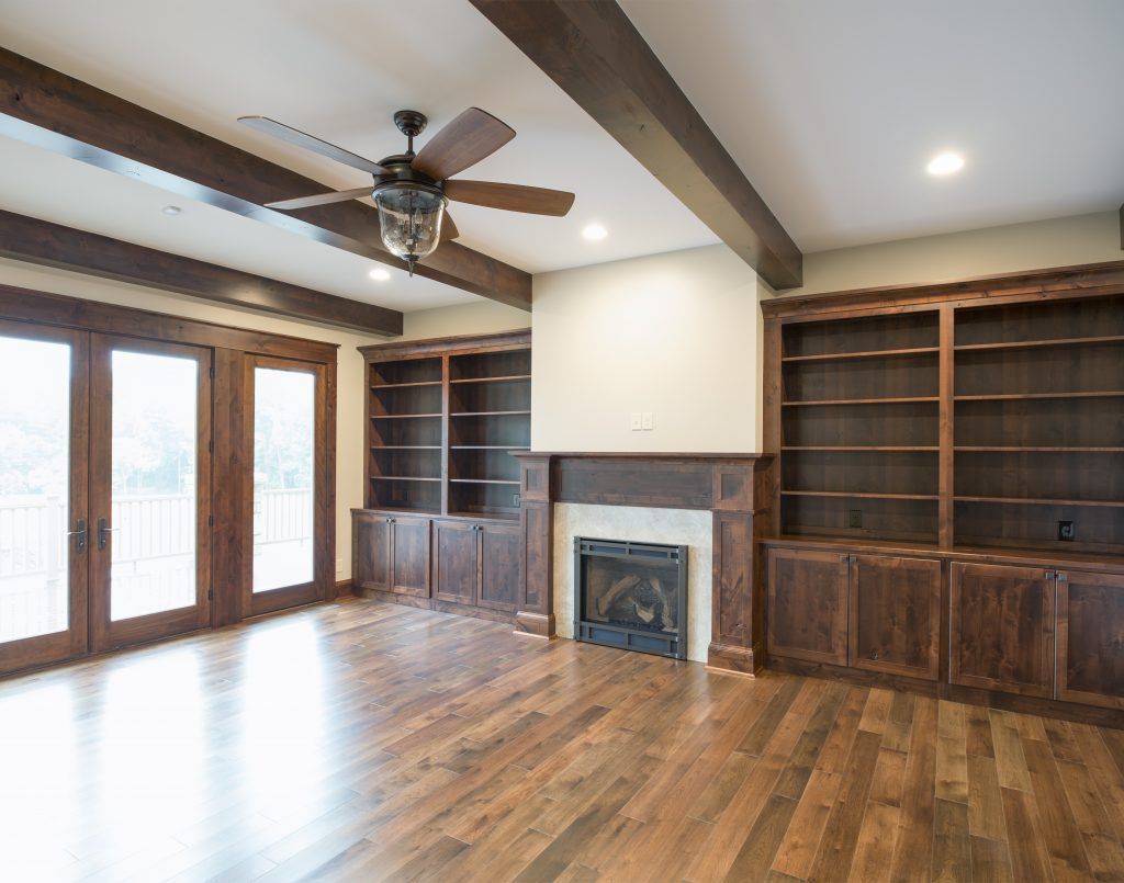 An empty living room with a fireplace and ceiling fan.