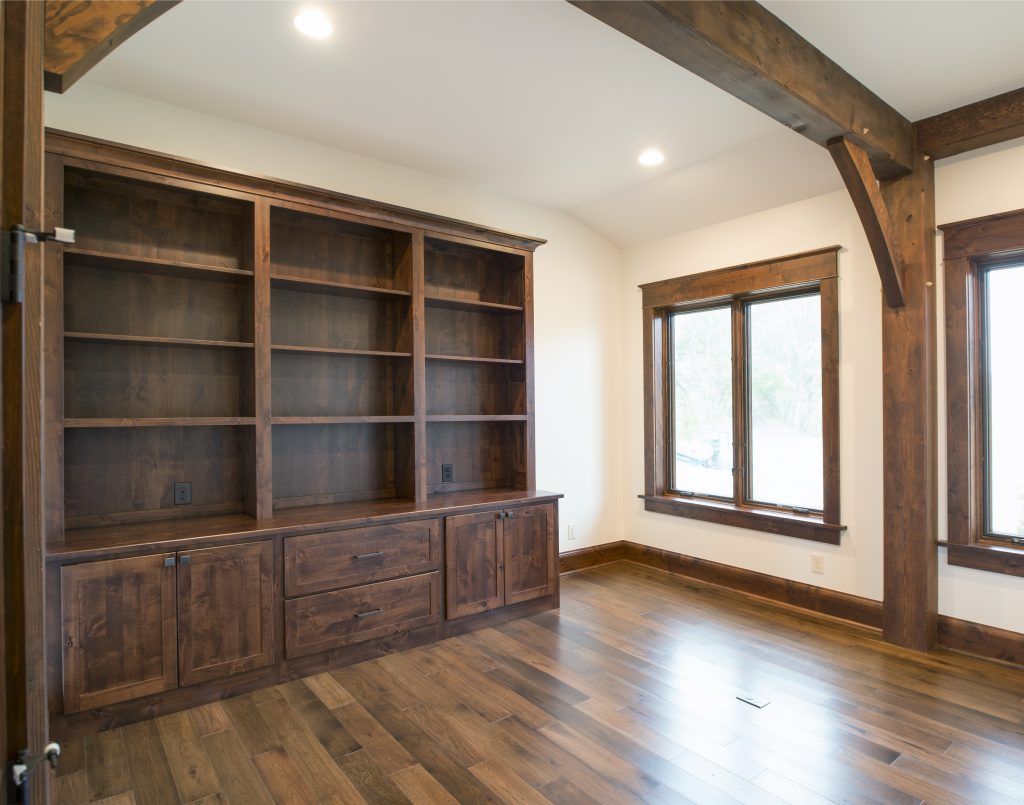 An empty room with hardwood floors and wooden shelves.
