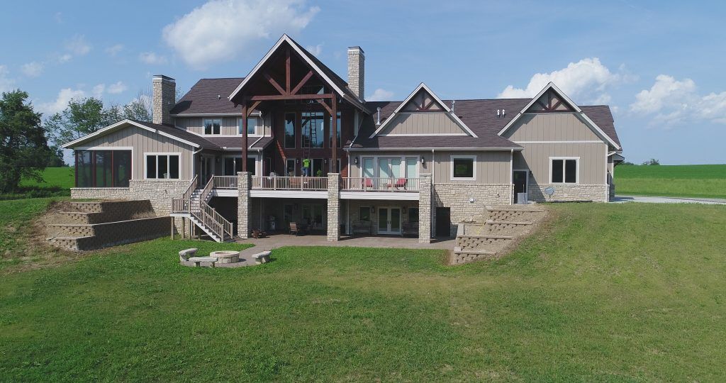 An aerial view of a large house in the middle of a grassy field.