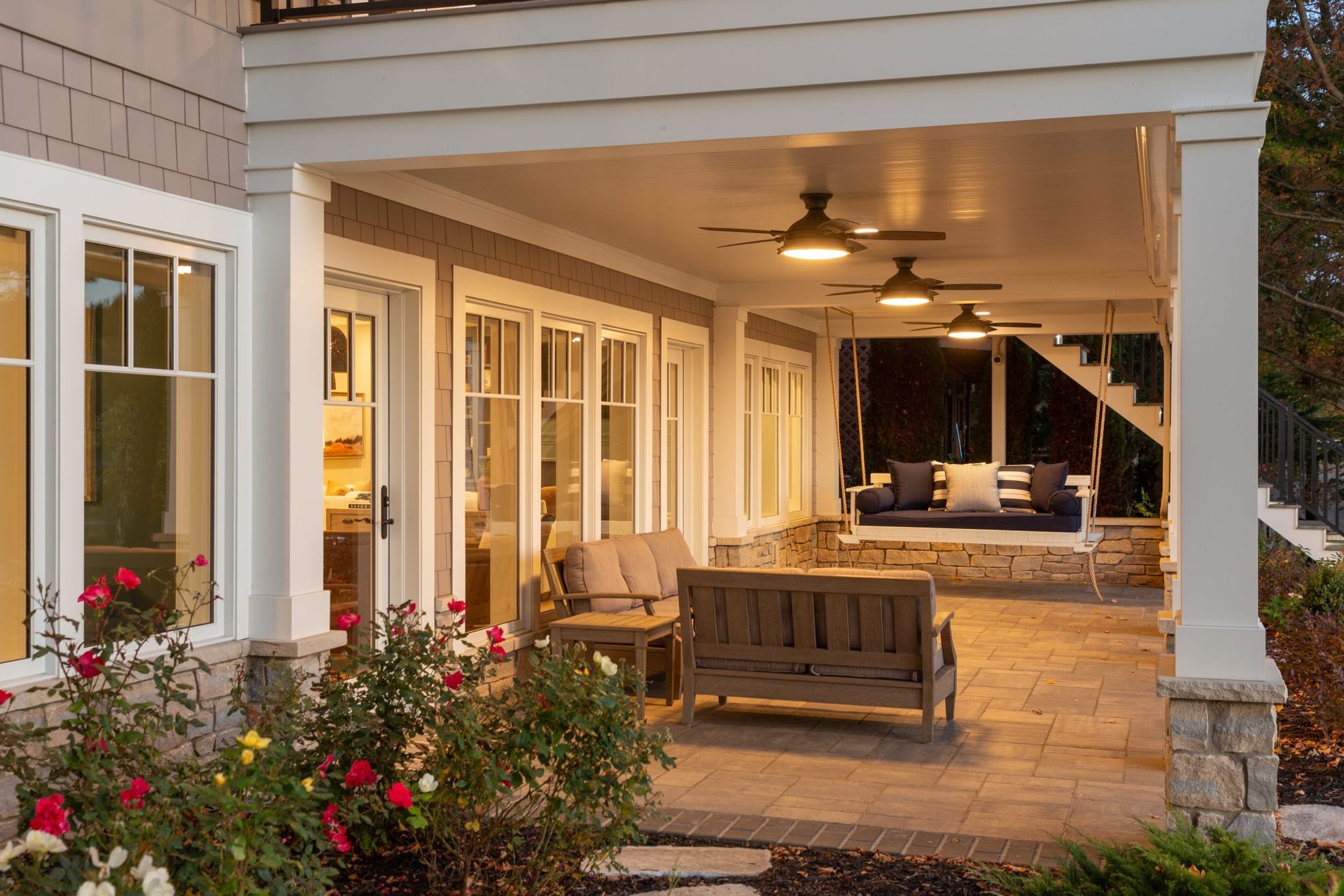 A porch with a swing and a ceiling fan