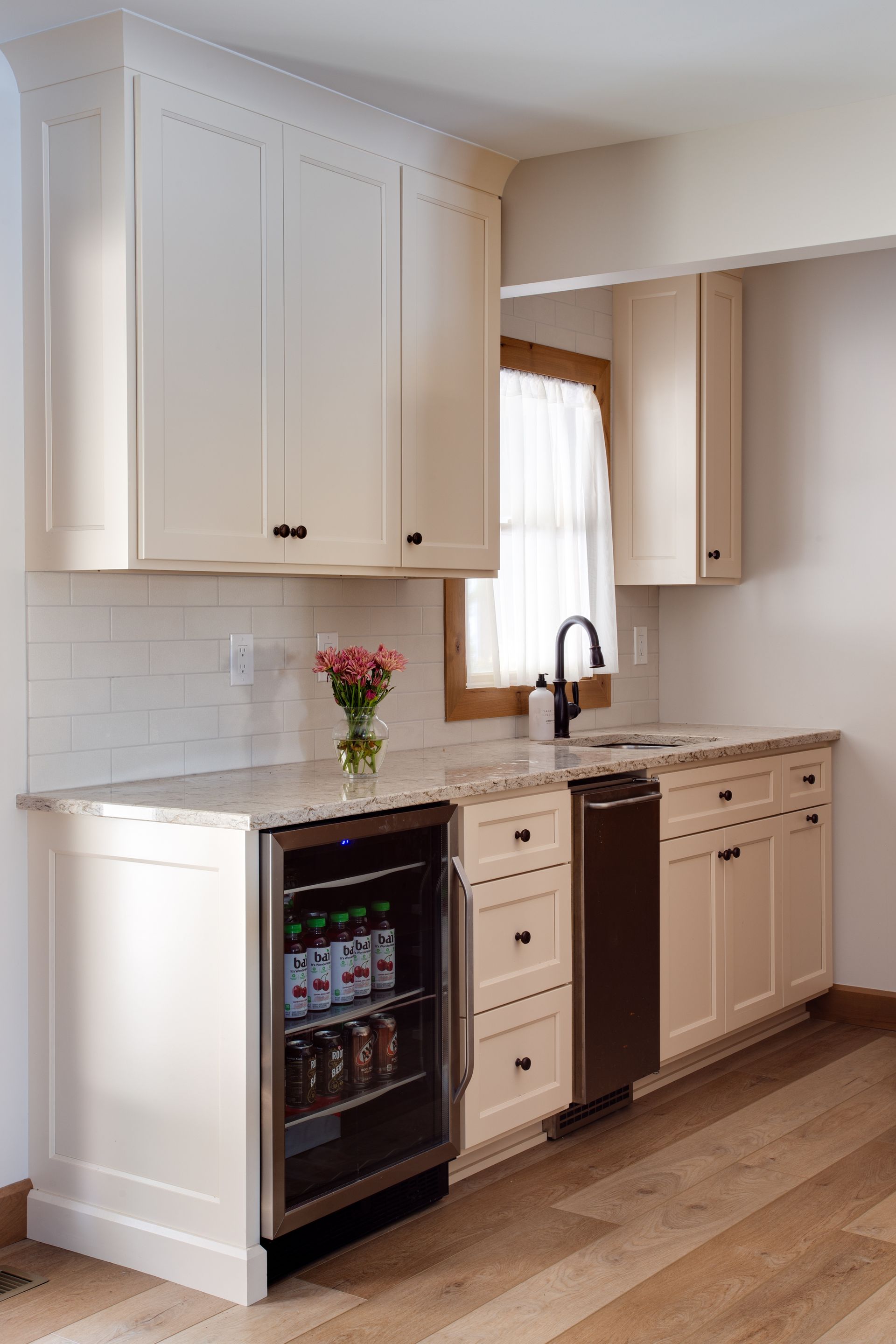 A kitchen with white cabinets and a stainless steel refrigerator.