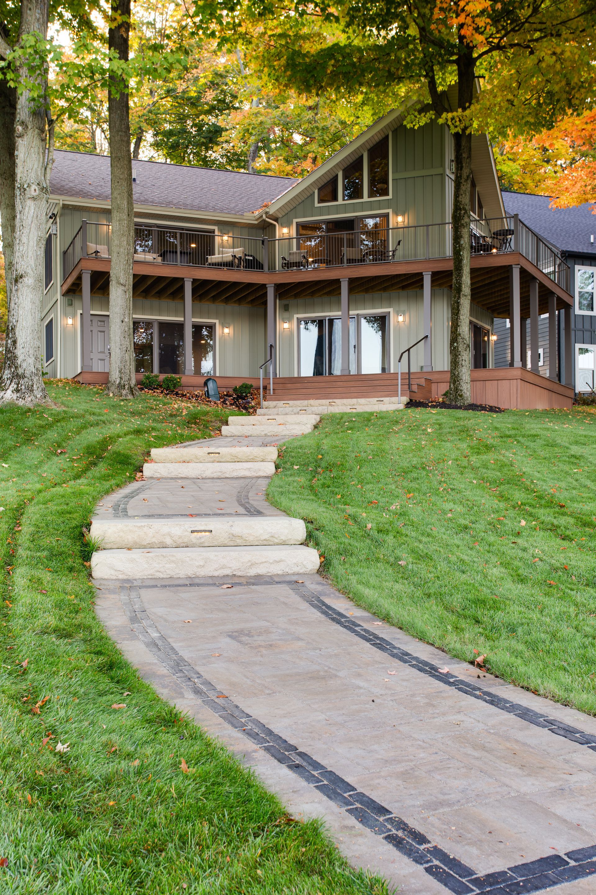 A concrete walkway leading to a large house on a hill.