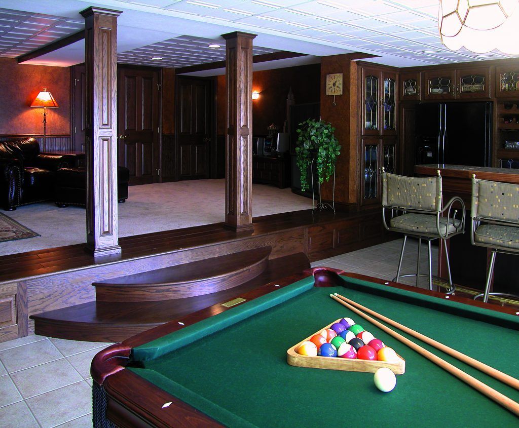 A pool table with balls and cues in a living room