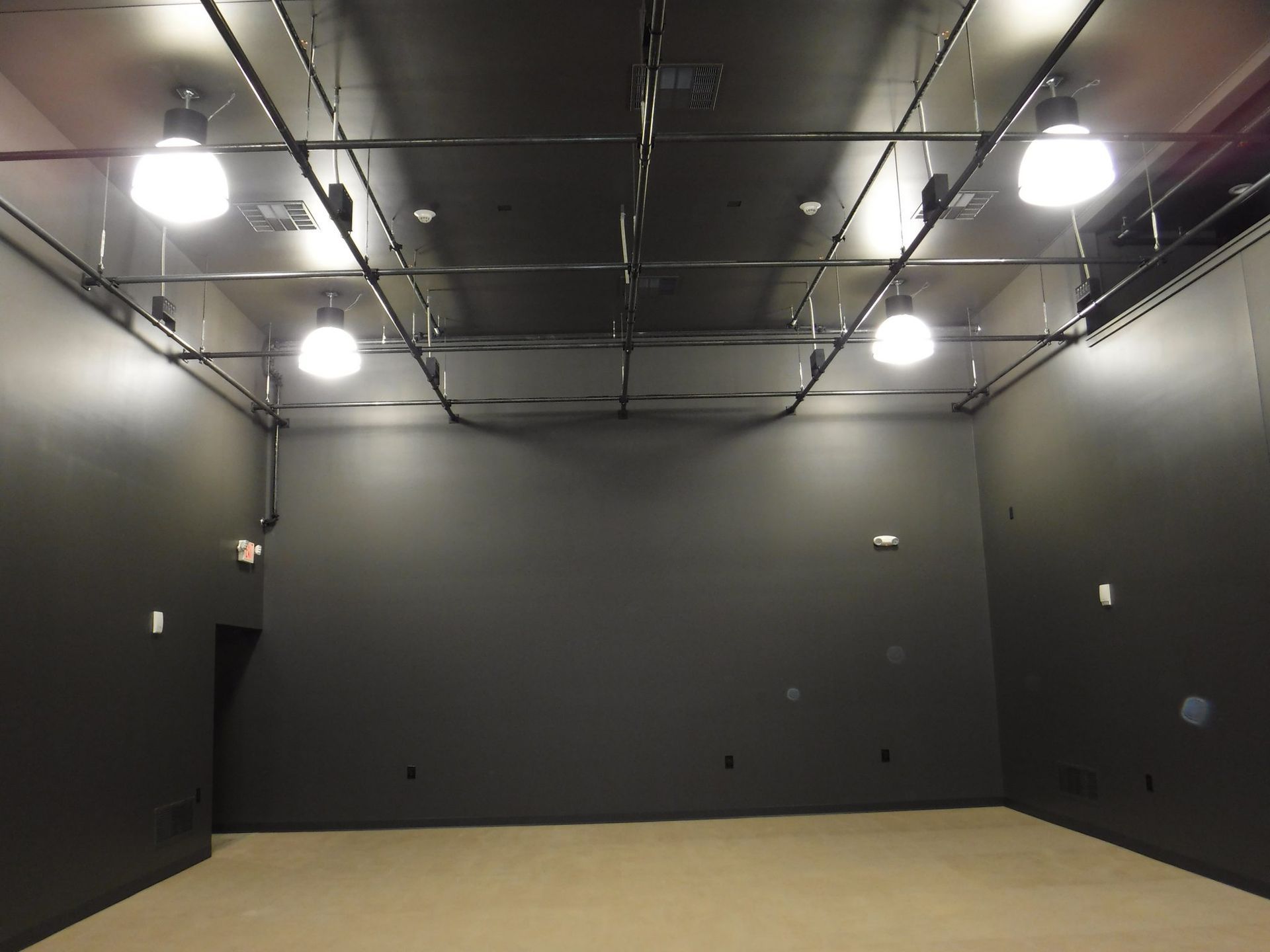 An empty room with black walls and lights on the ceiling.