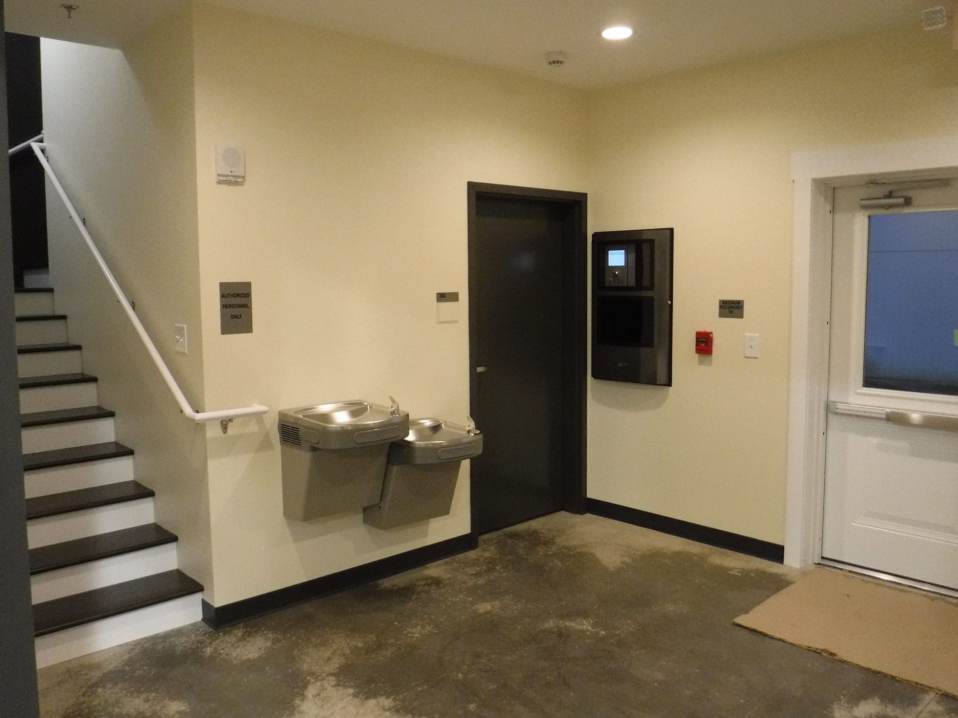 A hallway with stairs and a water fountain.