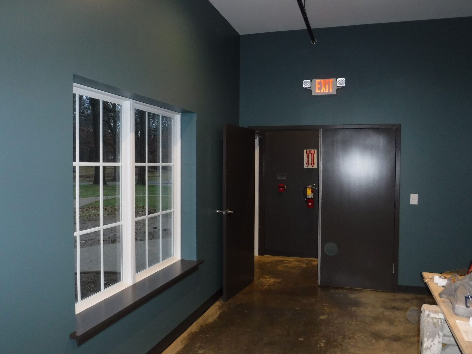 A hallway with a window and an exit sign.