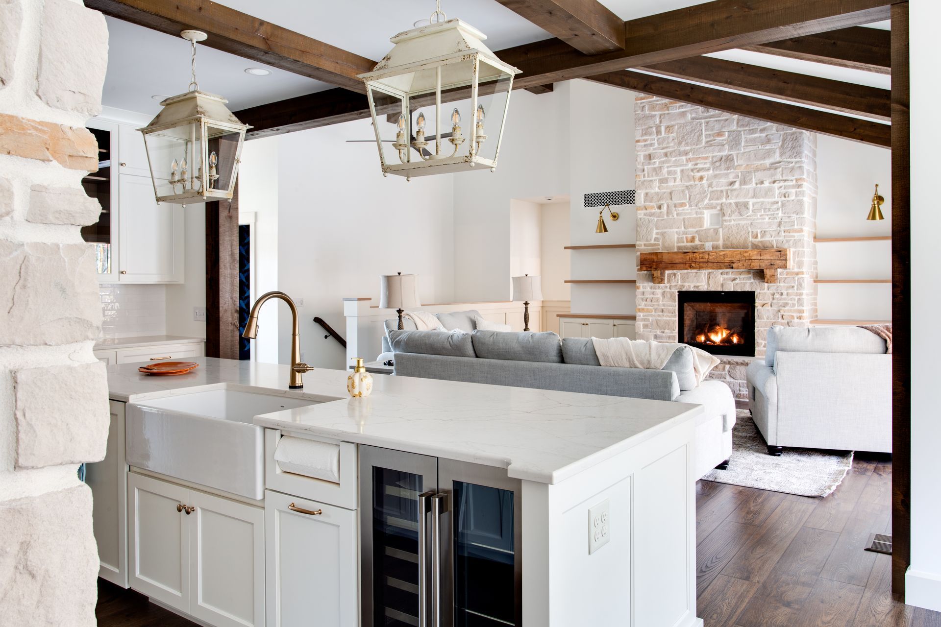 A kitchen with white cabinets, a sink, a refrigerator and a fireplace.