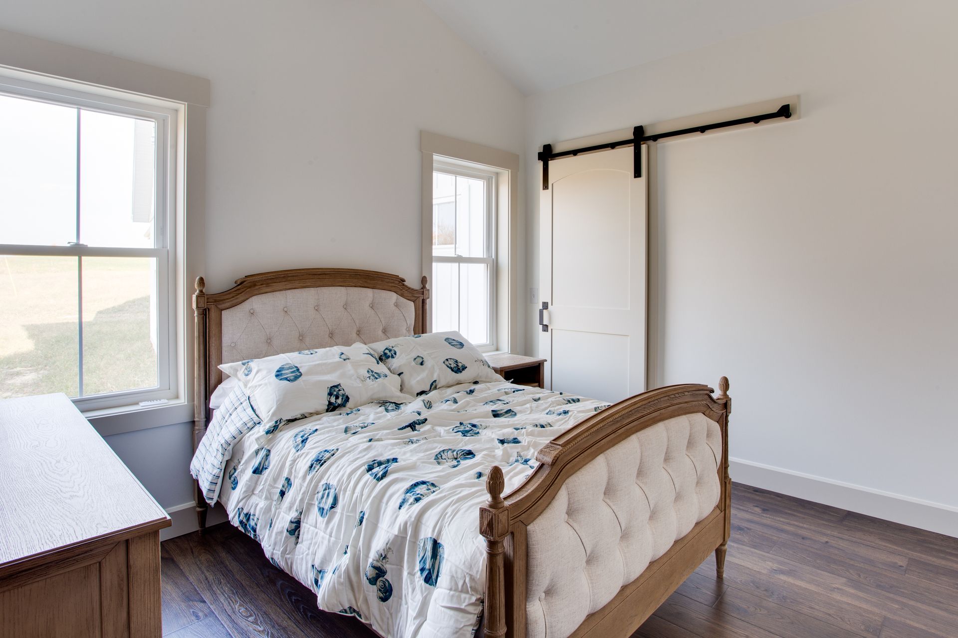 A bedroom with a bed, dresser, and sliding barn door.