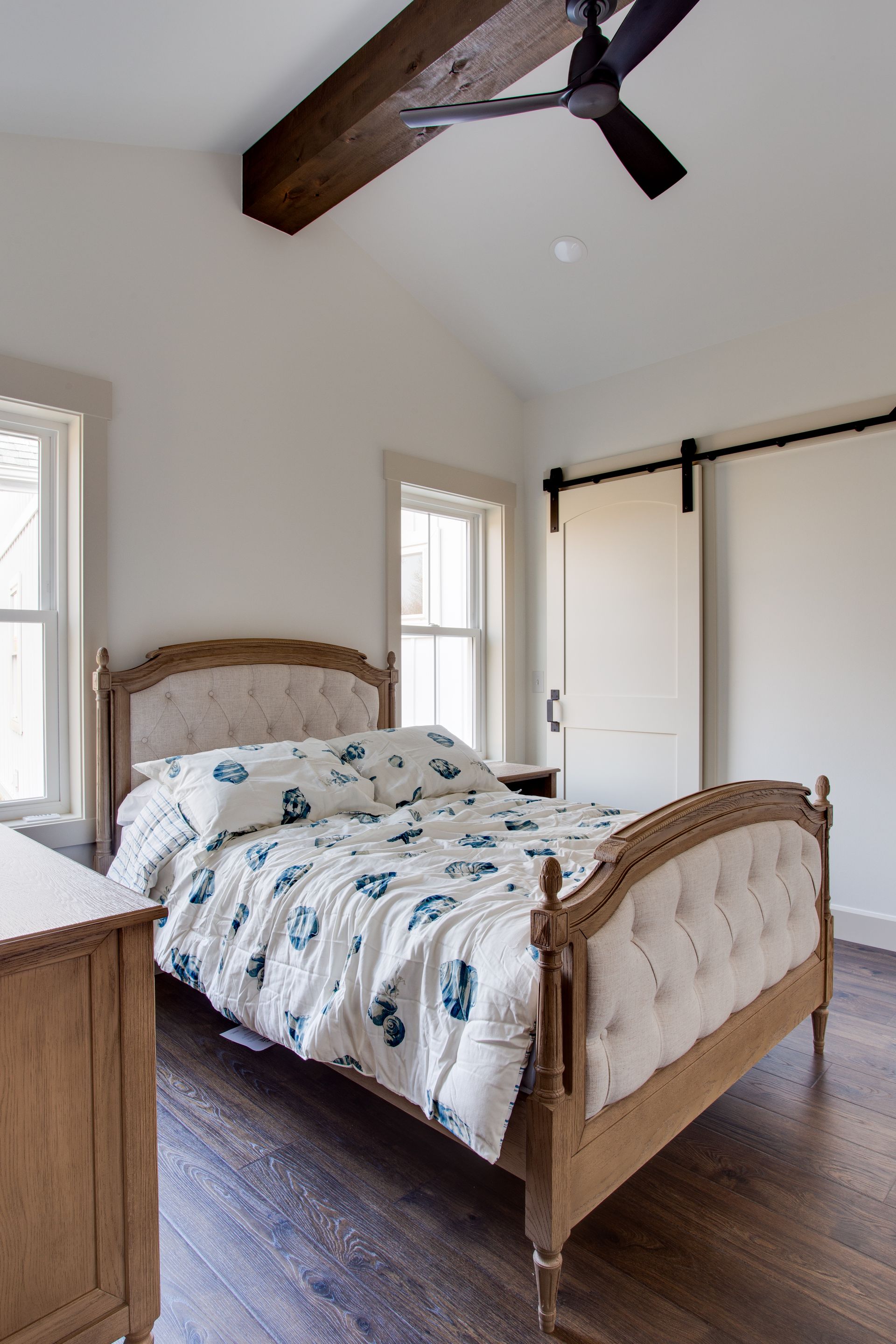 A bedroom with a bed, dresser, and ceiling fan.