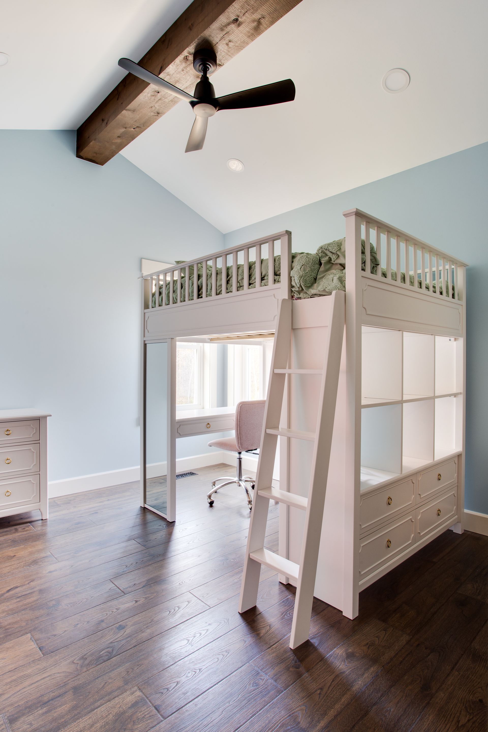 A bunk bed with a ladder in a bedroom with a ceiling fan.
