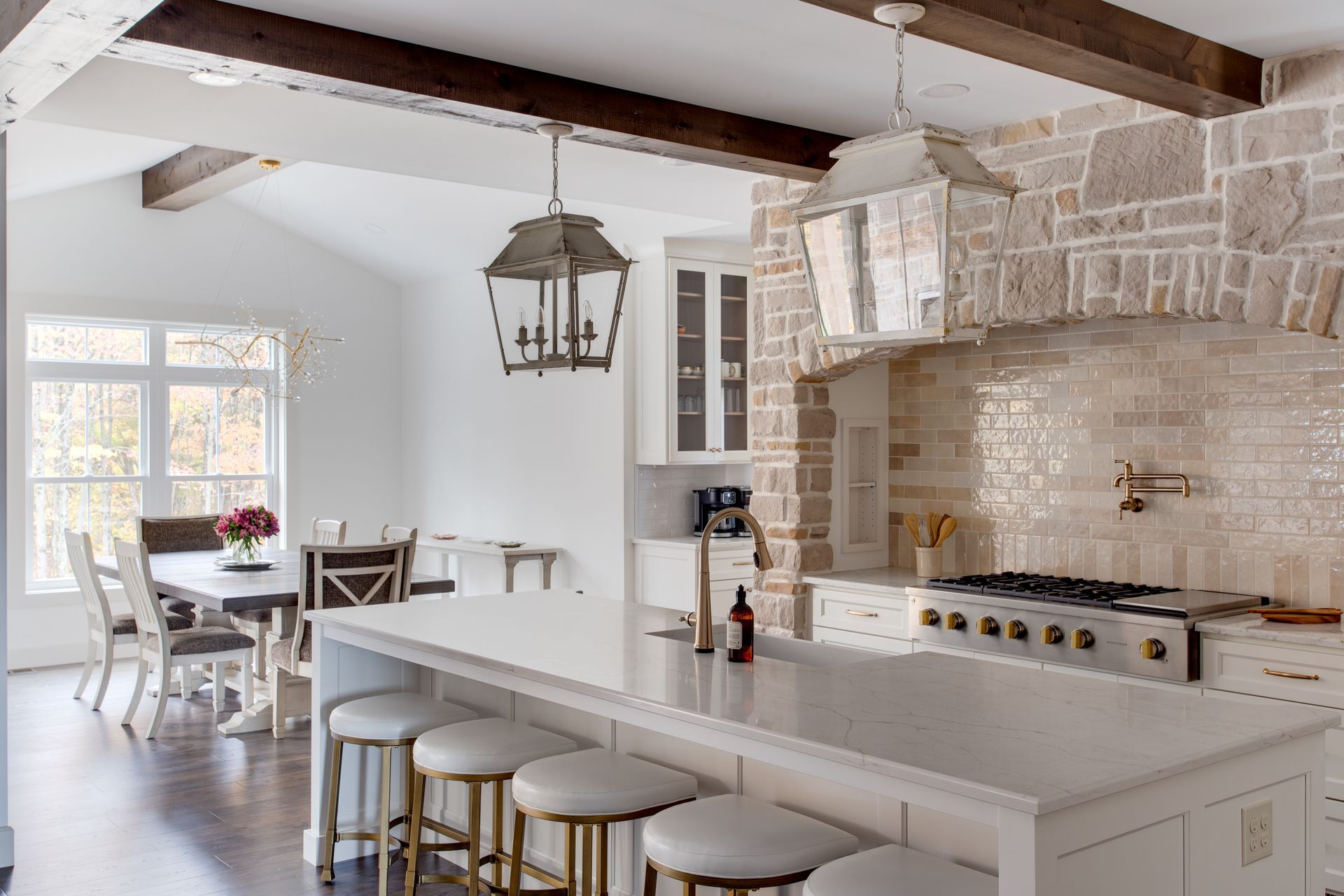A kitchen with a large island and stools and a dining room in the background.