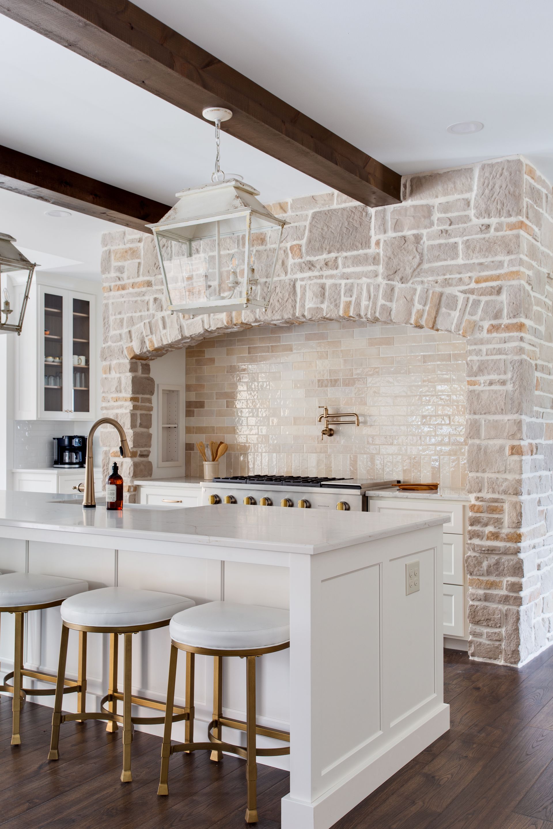 A kitchen with a large island, stools and a stove.