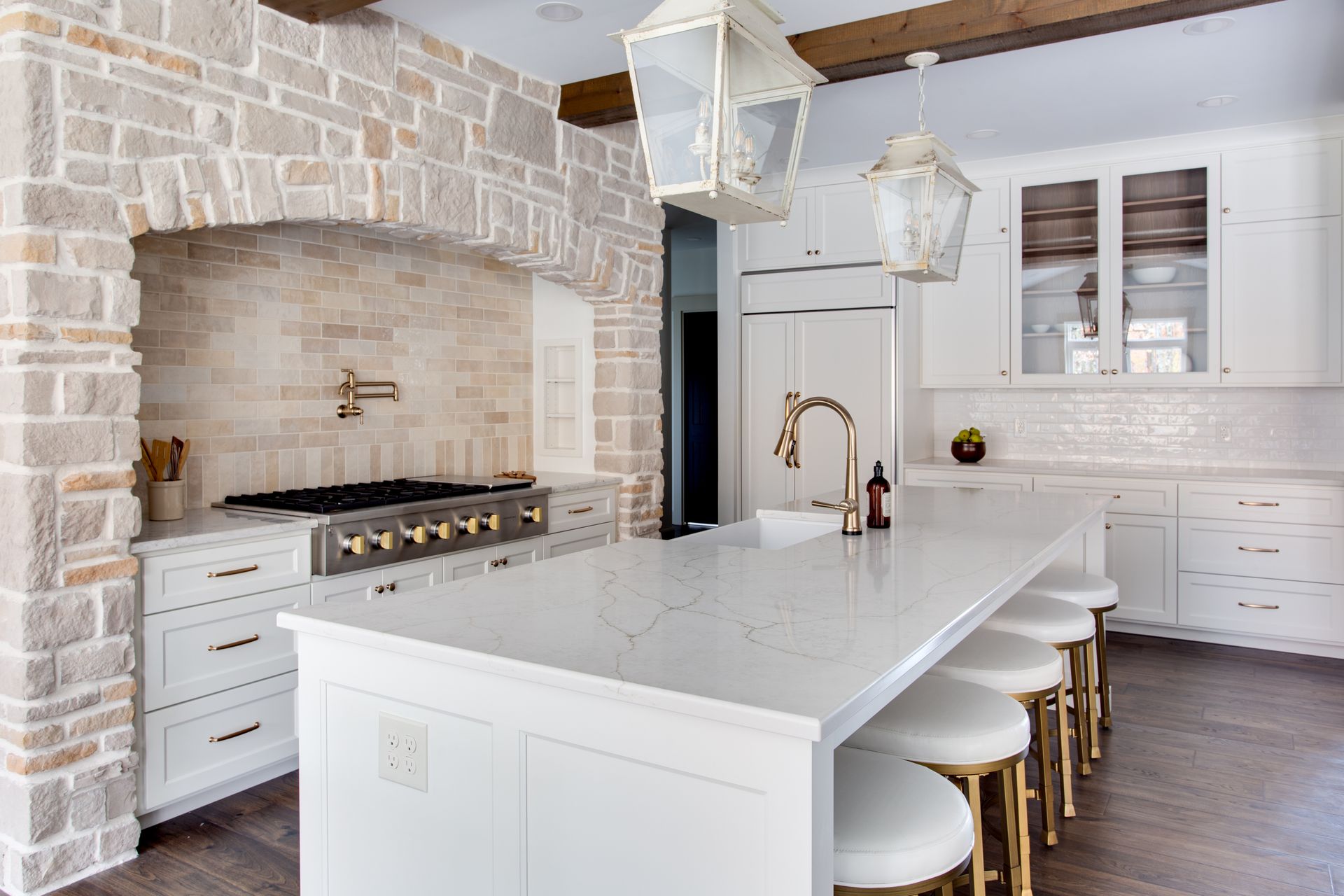 A kitchen with white cabinets, a large island, a stove and a sink.