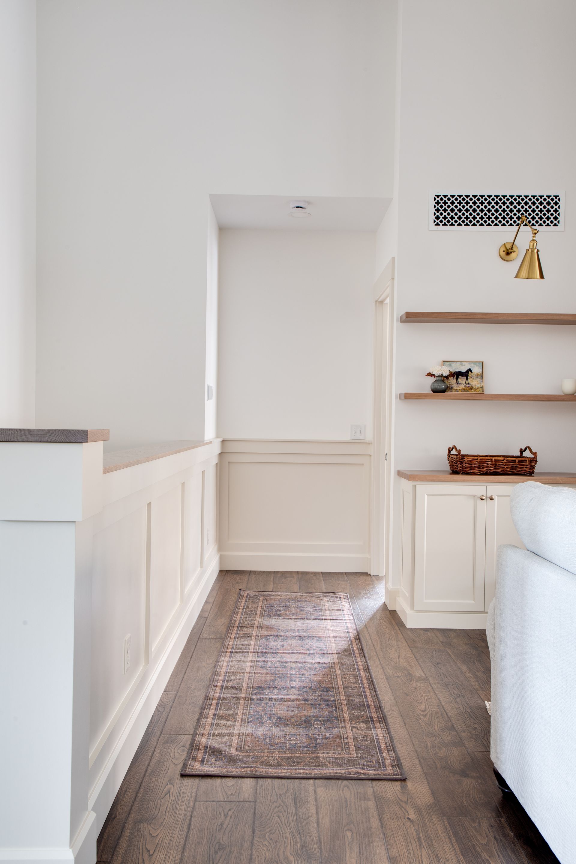 A long hallway leading to a living room with a rug on the floor.