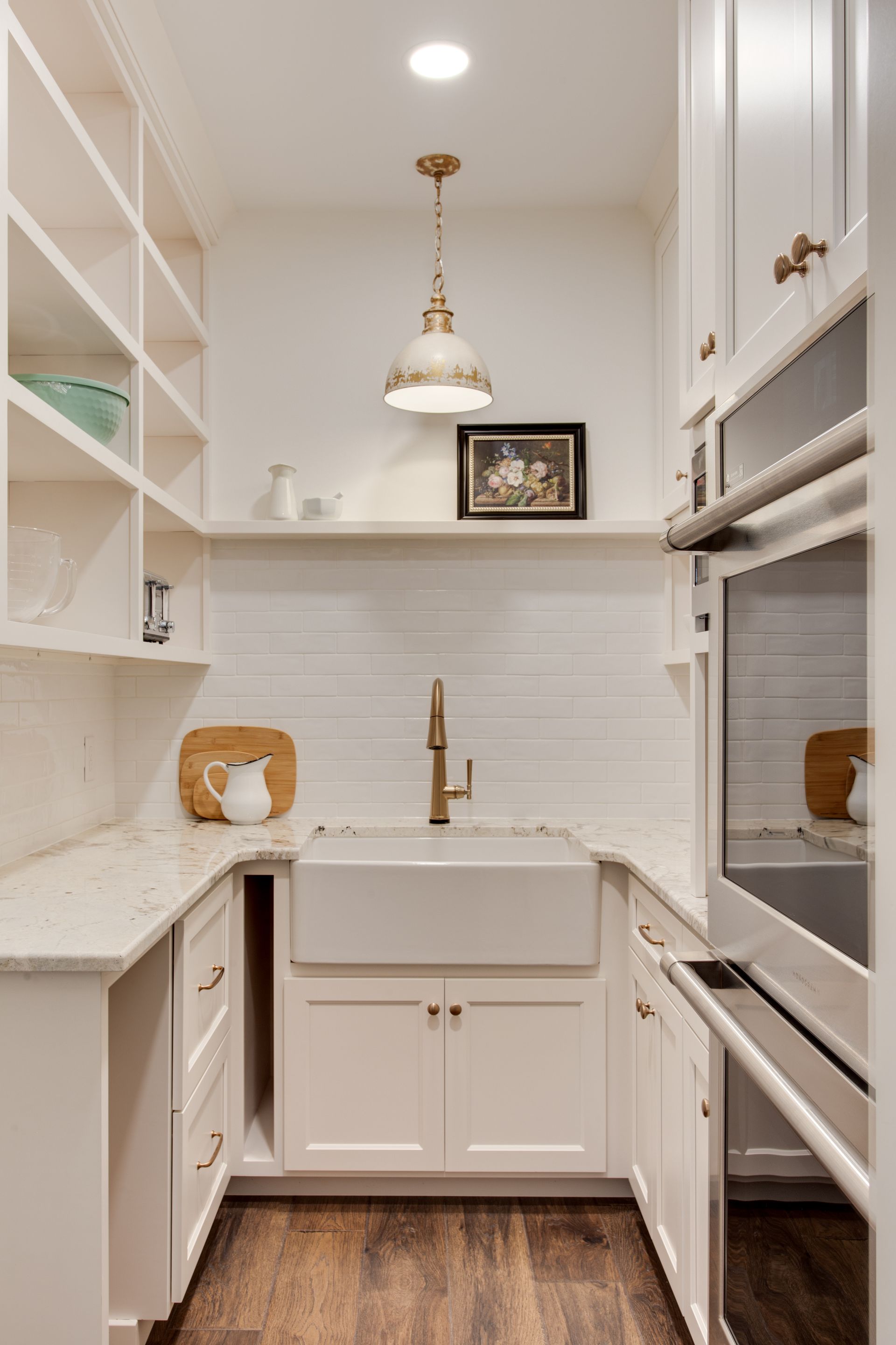 A kitchen with white cabinets , a sink , and a stainless steel oven.