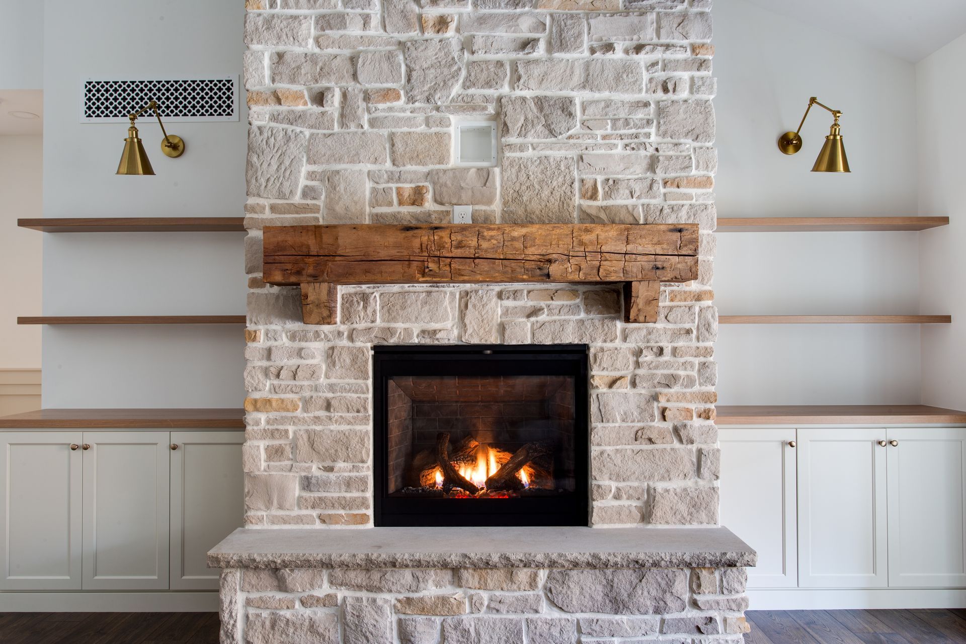A brick fireplace with a wooden mantle in a living room.