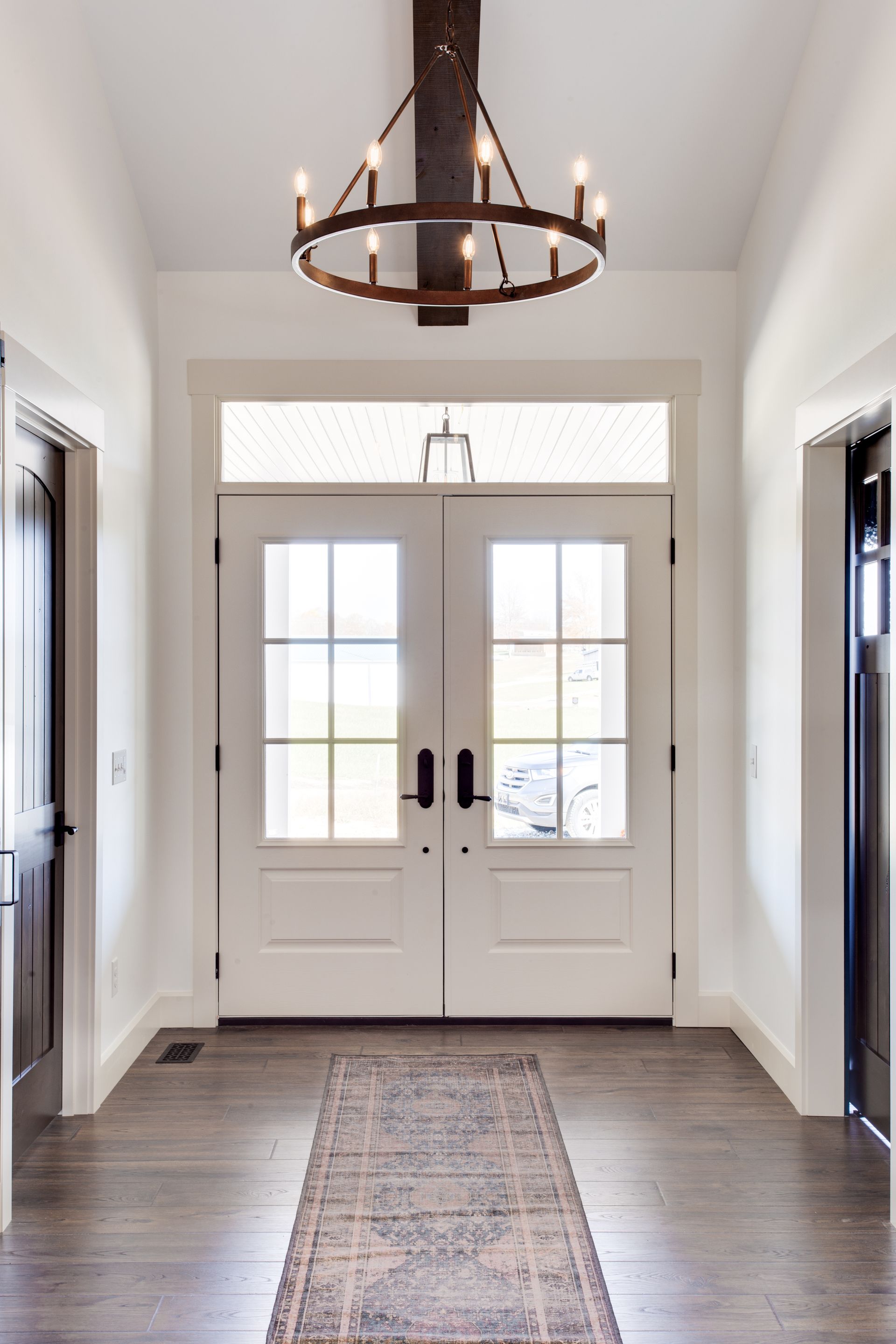 A hallway with a rug and a chandelier hanging from the ceiling.