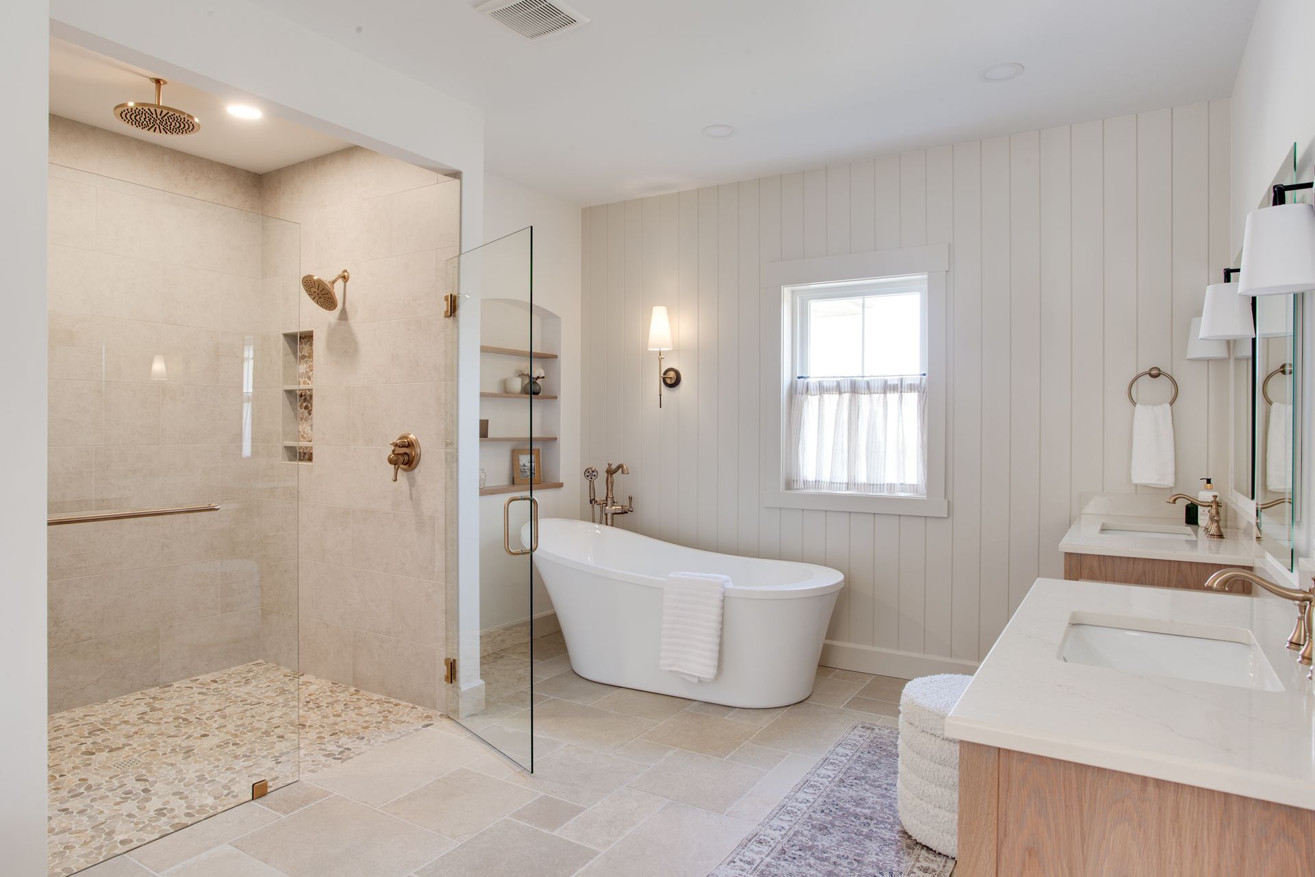 A bathroom with a tub, sink, shower and window.
