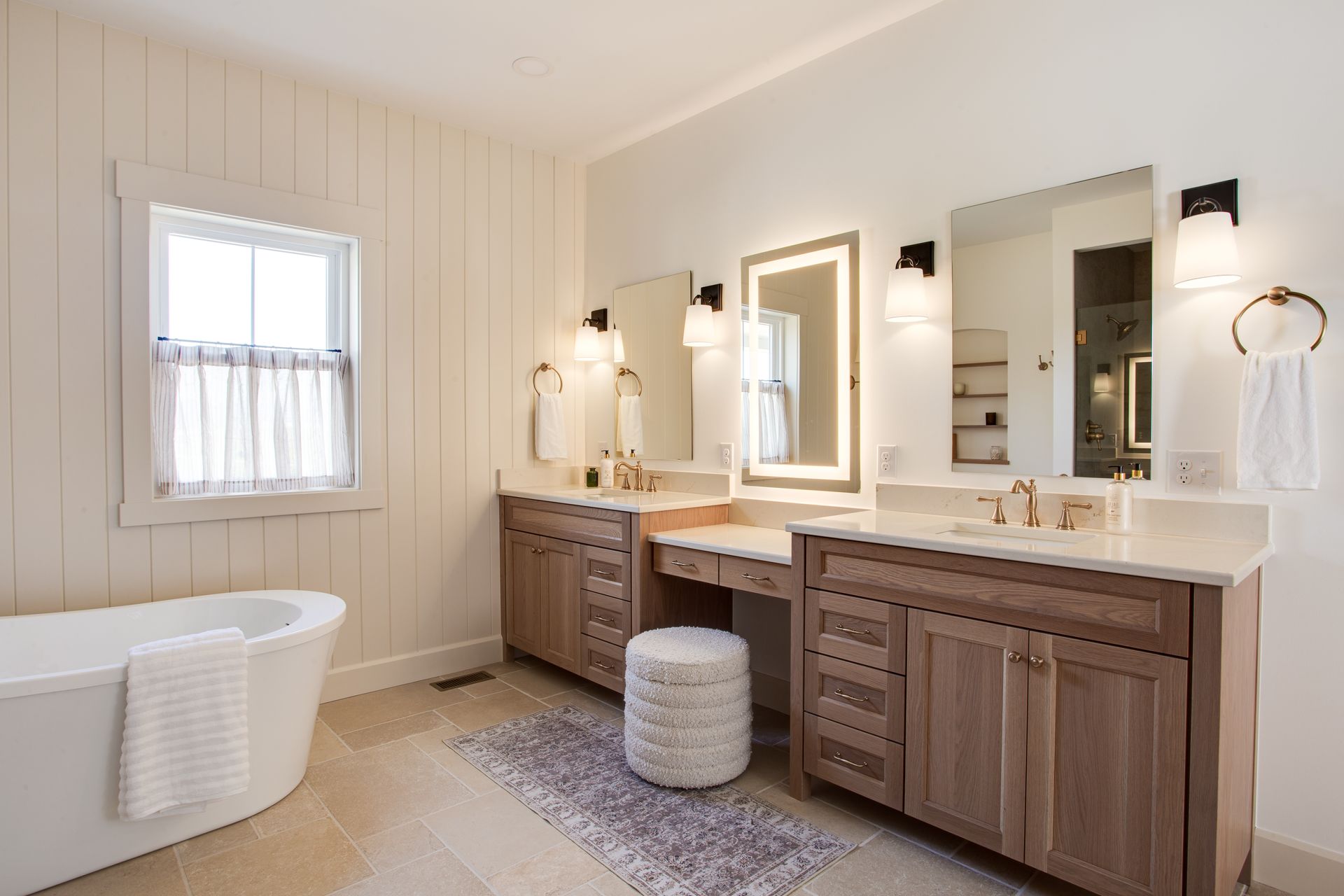 A bathroom with two sinks, a tub, and two mirrors.
