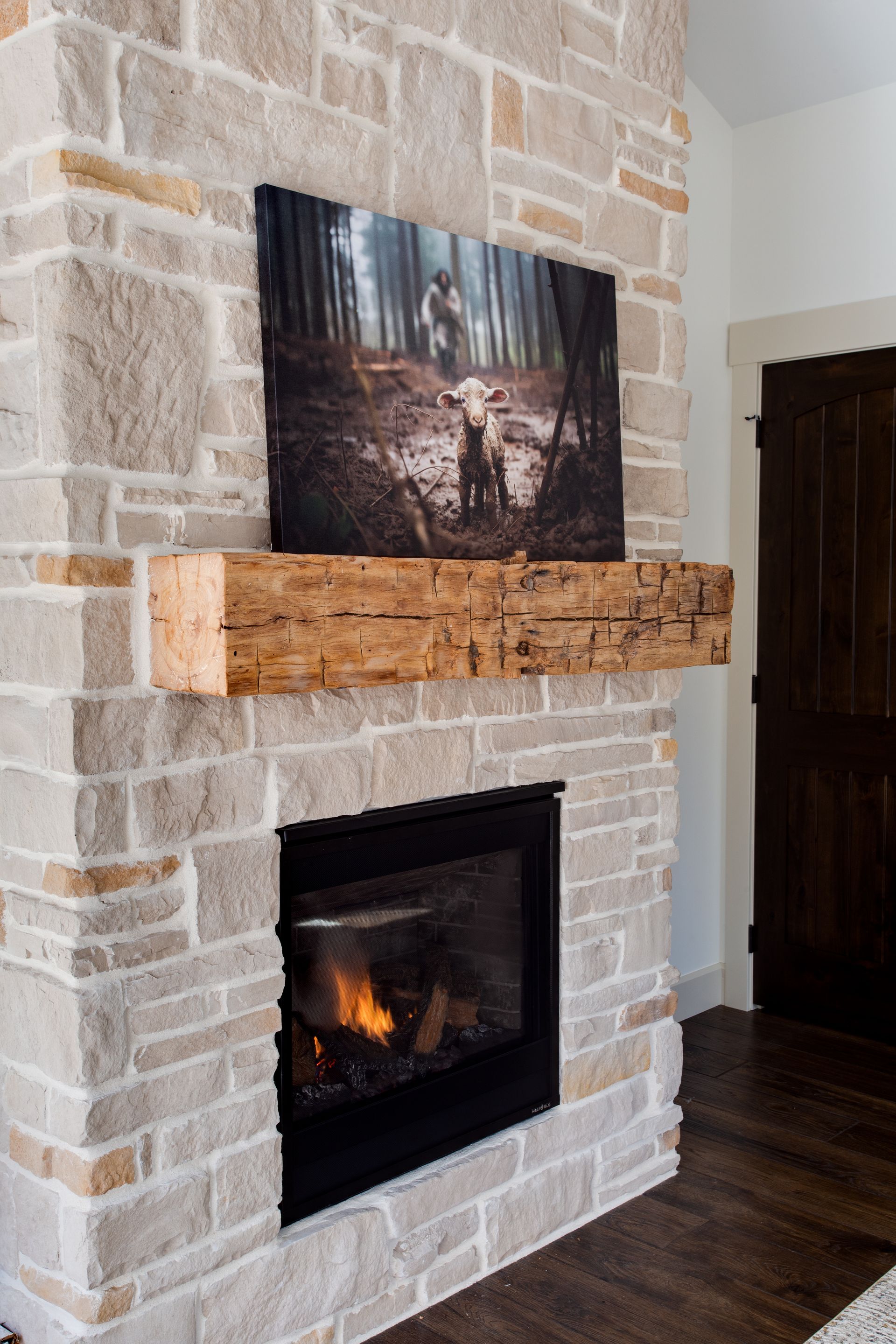 A fireplace with a wooden mantle and a picture on it.