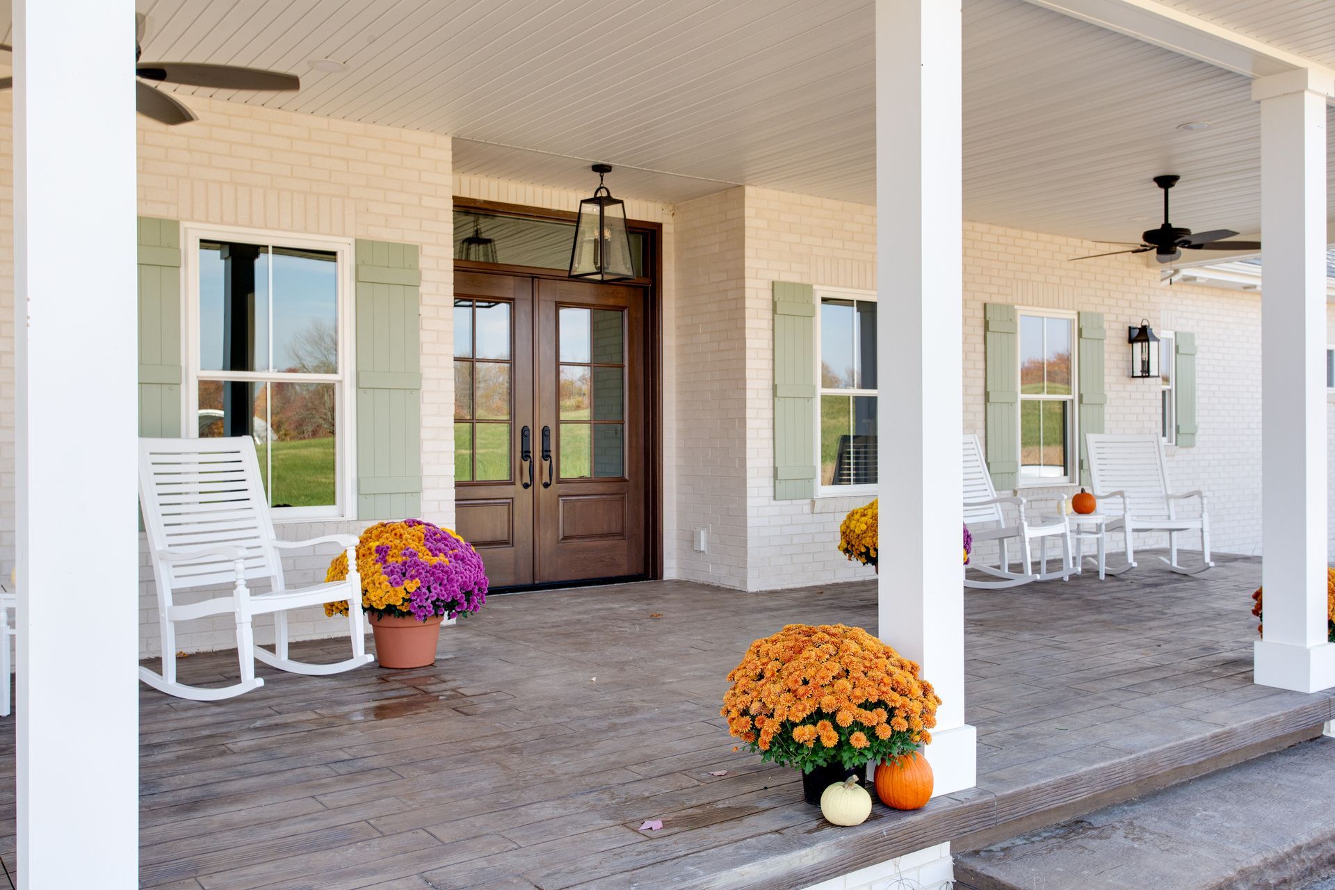 A porch with rocking chairs and flowers on it.