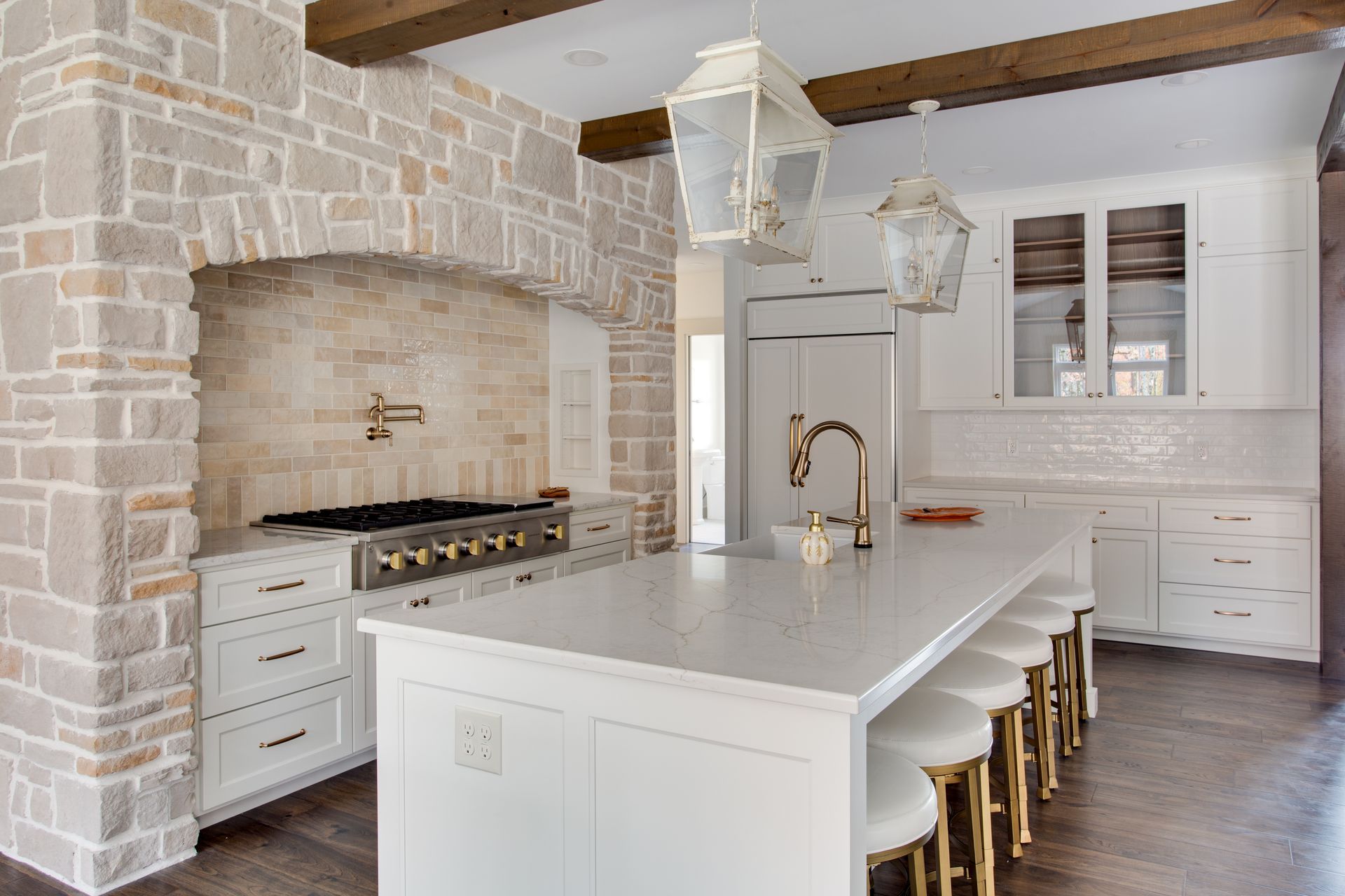 A kitchen with white cabinets, a large island, and a stove.