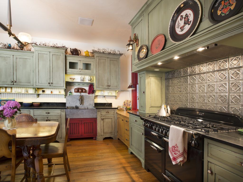 A kitchen with green cabinets and a black stove top oven.