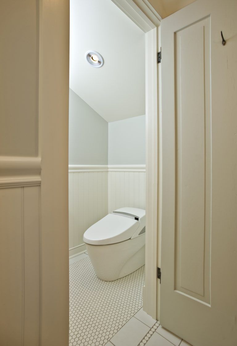 A toilet is sitting in a bathroom next to a door.