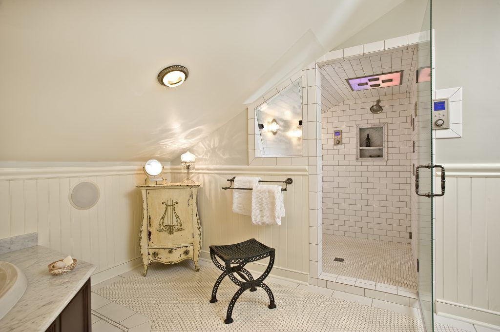 A bathroom with a walk in shower and a stool.