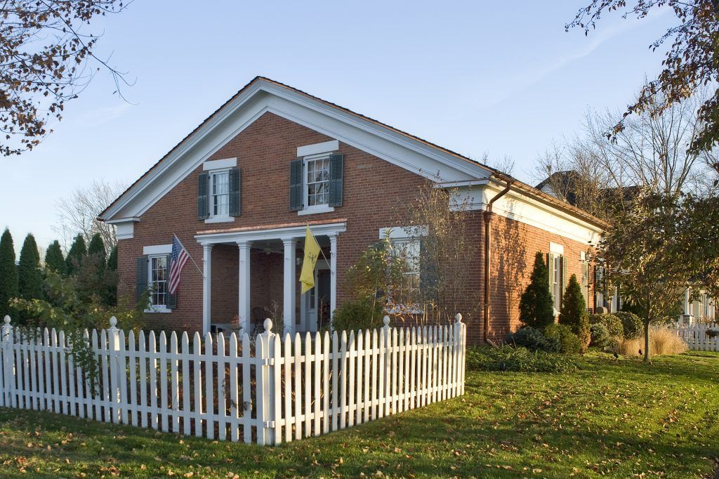 A brick house with a white picket fence around it.