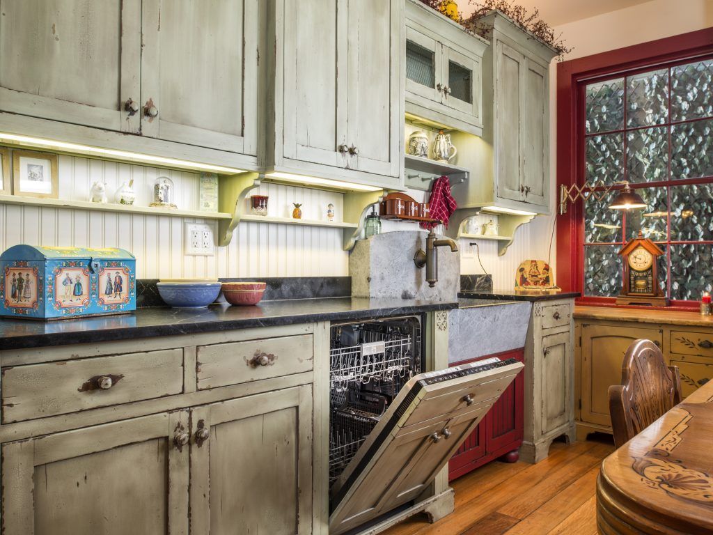 A kitchen with a dishwasher open and a clock on the counter.
