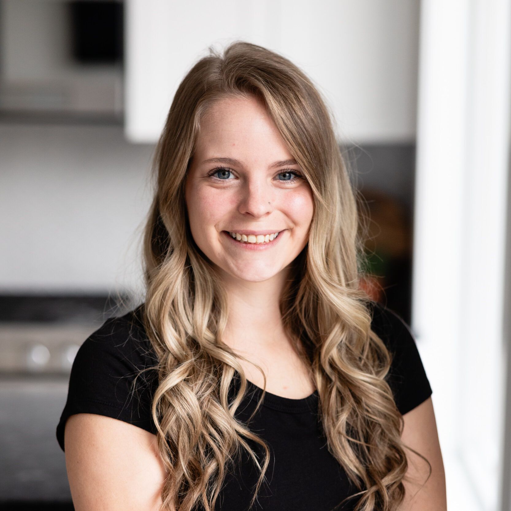 The woman is wearing a black shirt and smiling for the camera.