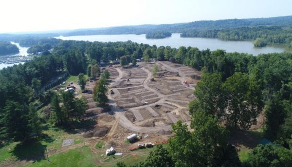 An aerial view of a park with trees and a lake in the background.