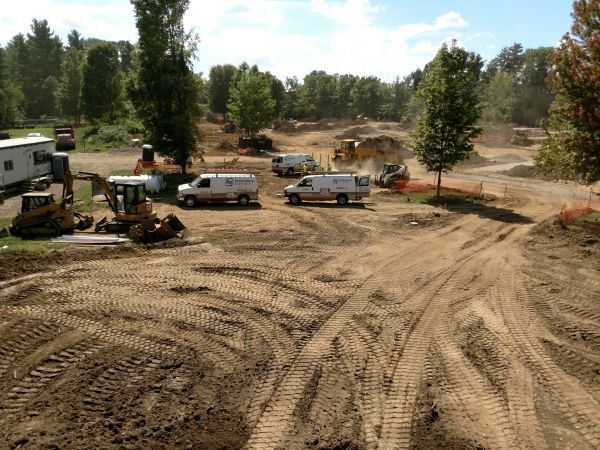 A lot of construction vehicles are parked in a dirt field.