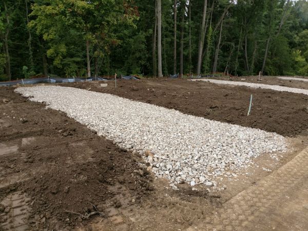 A pile of gravel is sitting in the middle of a dirt field.