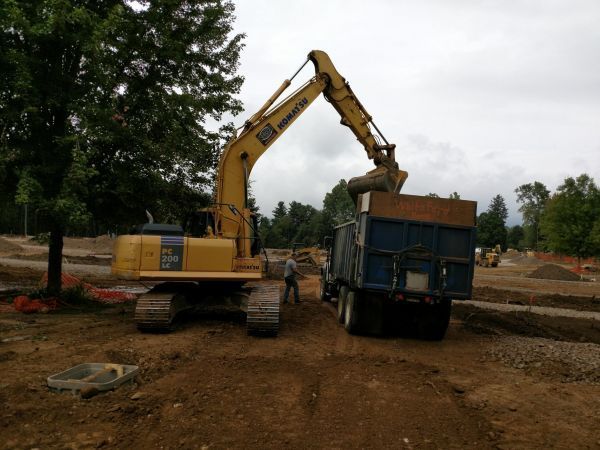 A Komatsu excavator is loading dirt into a dump truck.
