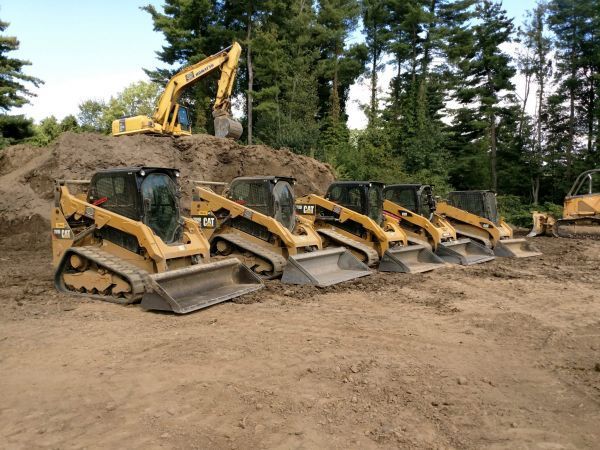 A row of bulldozers are parked in a dirt field.