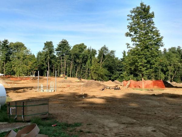 A large dirt field with trees in the background.